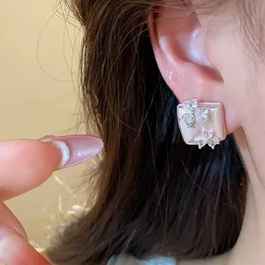 Detailed close-up showing a geometric square stud earring with delicate zircon flower design
