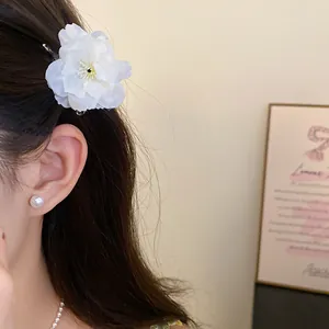 Detailed close-up showing a delicate white fabric flower hair clip on an Asian model