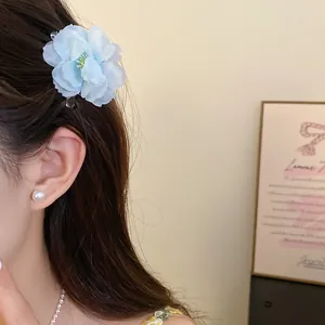 Close-up detail of a light blue fabric flower hair clip worn by a model in a lifestyle setting