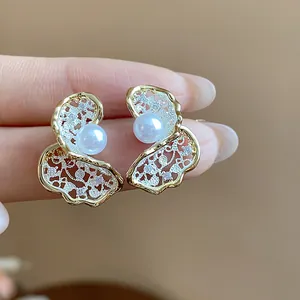 Close-up view of elegant 18K gold plated floral stud earrings with a pearl center