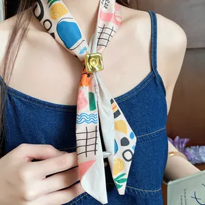 Close-up detail of a printed silk scarf with a golden square slider on a model's neck