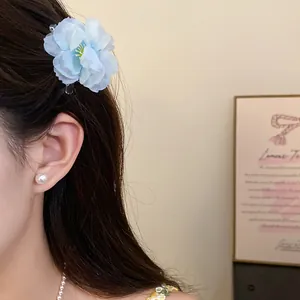 Close-up of an elegant blue fabric flower hair clip worn as a stylish side accessory.
