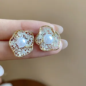 Macro detail of elegant 18K gold-plated flower stud earrings with a white center pearl