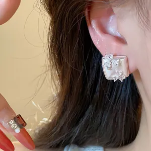 Elegant close-up of a geometric square stud earring with delicate zirconia flower accents