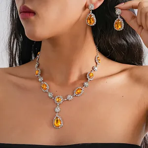 Close-up of vintage teardrop orange rhinestone necklace and earring set on model