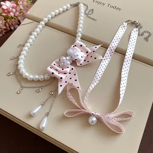 Dettaglio della collana di perle con fiocco di nastro rosa a pois su scatola regalo
