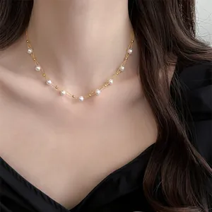 Detailed view of an elegant gold beaded necklace with white pearls on a female neck