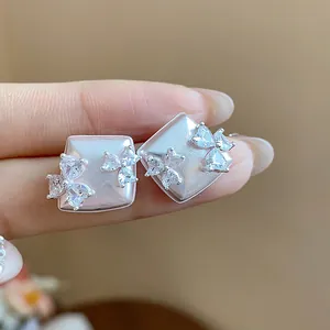 Close-up of geometric silver stud earrings with sparkling crystal flower accents