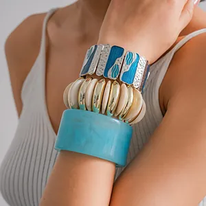 Dettaglio di un bracciale in resina blu e un bracciale dorato geometrico a strati