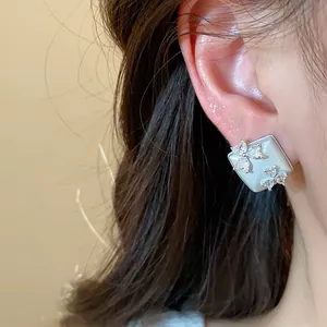 Close-up of elegant square earring with zirconia flowers worn on model's ear