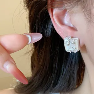 Close-up of geometric square ear stud with sparkling zircon flower design elements