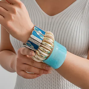 Dettaglio di braccialetti boho sovrapposti con smalto blu e polsino in resina su modella