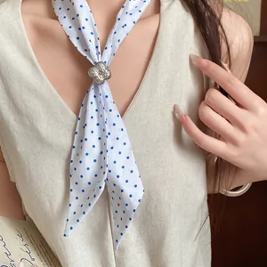 Close-up of a blue polka dot silk scarf necklace with silver flower ring accessory