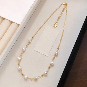 Close-up of elegant gold necklace featuring spaced white pearls on a display tray.