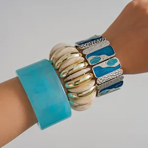 Dettaglio ravvicinato di un bracciale rigido in resina blu con braccialetti smaltati geometrici