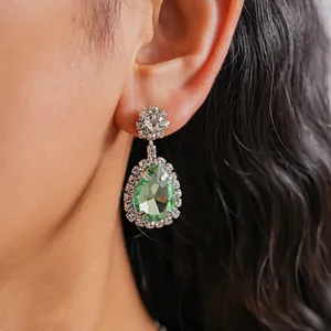 Close-up of vintage palace style light green water drop earrings on model's ear