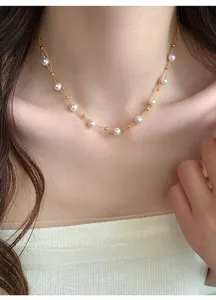 Close-up detail of a delicate French style double-layer gold necklace with white pearls