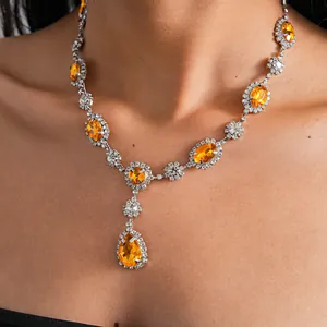 Close-up of retro necklace featuring vibrant orange oval and pear-shaped gemstones.