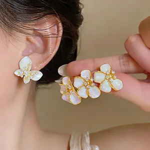 Detailed close-up of elegant French style pearlescent flower and butterfly stud earrings