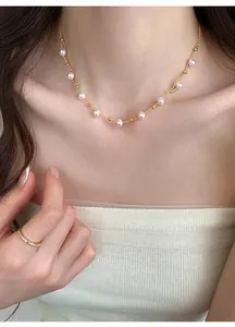 Detail shot of a double-layered gold pearl necklace on a model's collarbone.