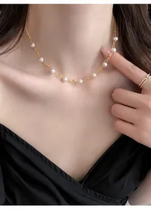 Elegant double-layered gold-toned necklace featuring white pearl beads worn on collarbone