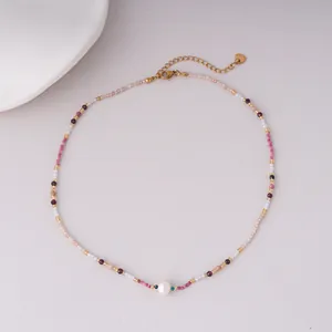 Close-up detail of colorful beaded necklace with a central pearl and gold chain.
