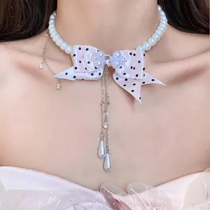 Primo piano di una elegante collana di perle con fiocco rosa a pois e pendenti
