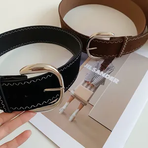 Detail view of black and brown leather belts with white zigzag stitching and silver buckle.