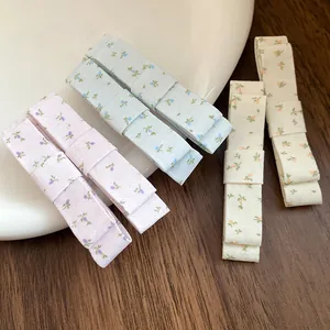 Detail view of Korean style floral fabric bow hair clips in pastel colors on wooden surface