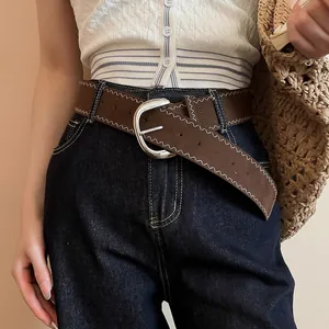 Close-up detail of a brown leather belt with white zigzag stitching and silver buckle
