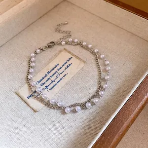 Elegant double-layer bracelet featuring a silver curb chain and delicate white pearls.