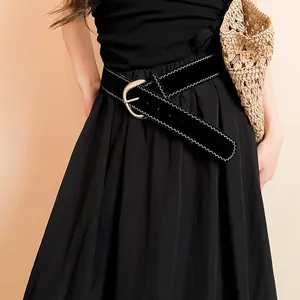 Close-up of a stylish black belt with white wavy stitching and a golden buckle on a dress.