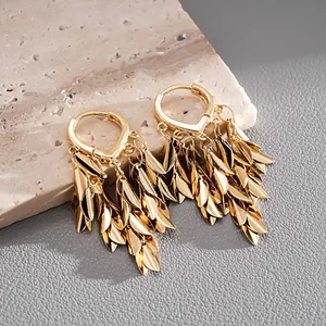 Detailed view of golden wheat ear leaf tassel hoop earrings on stone background