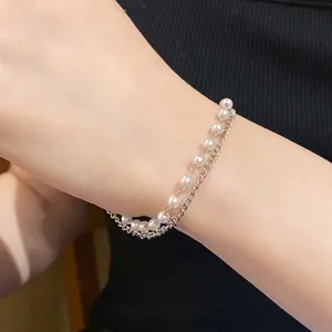 Elegant minimalist double-layer bracelet with white pearls and metal chain on model wrist