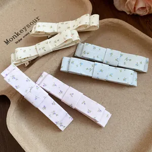 Detailed shot of floral print fabric bow hair clips in cream, blue and purple colors