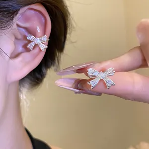 Elegante earcuff a fiocco in argento con zirconi scintillanti mostrato indossato e in mano