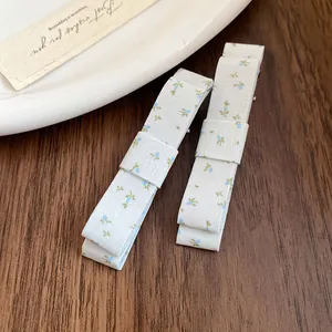 Close-up detail of floral print fabric bow hair clips set on a rustic wooden surface