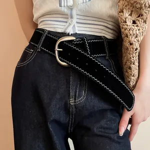 Close-up detail of black leather belt featuring white zigzag stitching and silver metal buckle