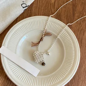 Close-up of a silver beaded necklace with a textured heart pendant and bead charm