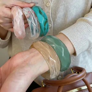 Close-up detail of multi-colored faceted acrylic marble bangles on a model's wrist