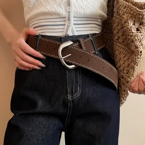 Close-up of retro brown leather belt with white zigzag stitching and silver oval buckle.