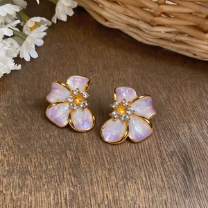 Detailed macro shot of elegant pearlescent purple flower earrings with gold edges