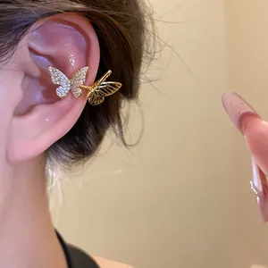 Primo piano di un ear cuff a farfalla dorata con zirconi scintillanti sull'orecchio.