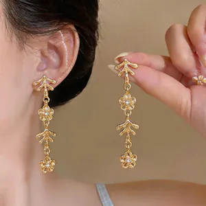 Eleganti orecchini pendenti vintage dorati con motivi floreali e accenti di cristallo scintillante