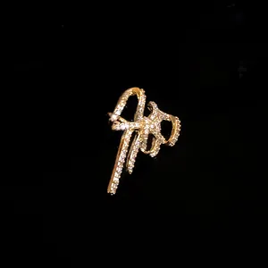 Dettaglio ravvicinato di un ear cuff dorato a forma di fiocco con zirconi scintillanti