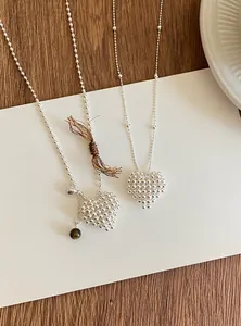 Detailed view of silver 3D beaded heart necklaces shown on a minimalist background card