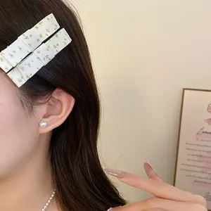 Close-up detail of floral fabric bow hair clip worn by model for sweet summer hair style