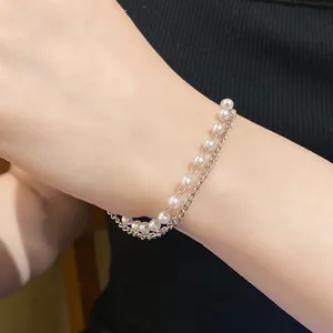 Close-up detail of elegant double-layered pearl and gold chain bracelet on a female wrist
