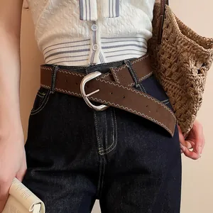 Detail view of a brown leather belt featuring white zigzag stitching and a silver buckle