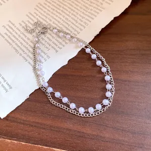 Elegant double-layer silver chain bracelet with delicate lavender pearl beads on vintage paper